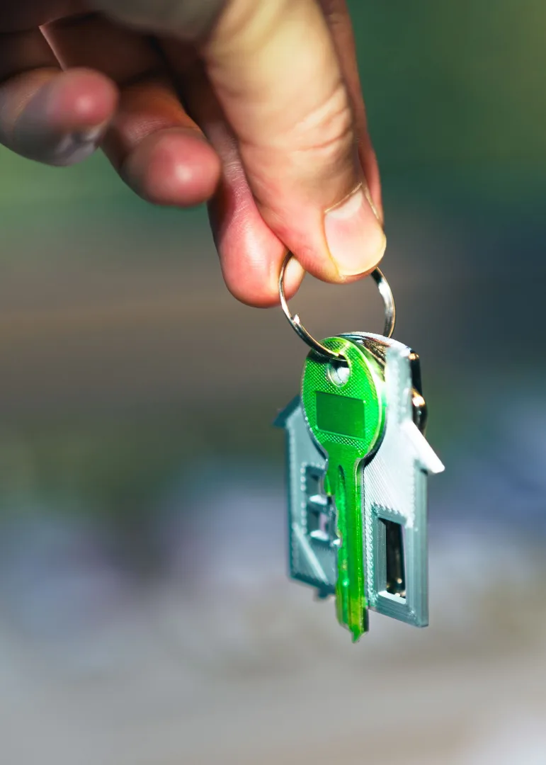 Mão segurando a chave da casa própria com chaveiro em formato de casa